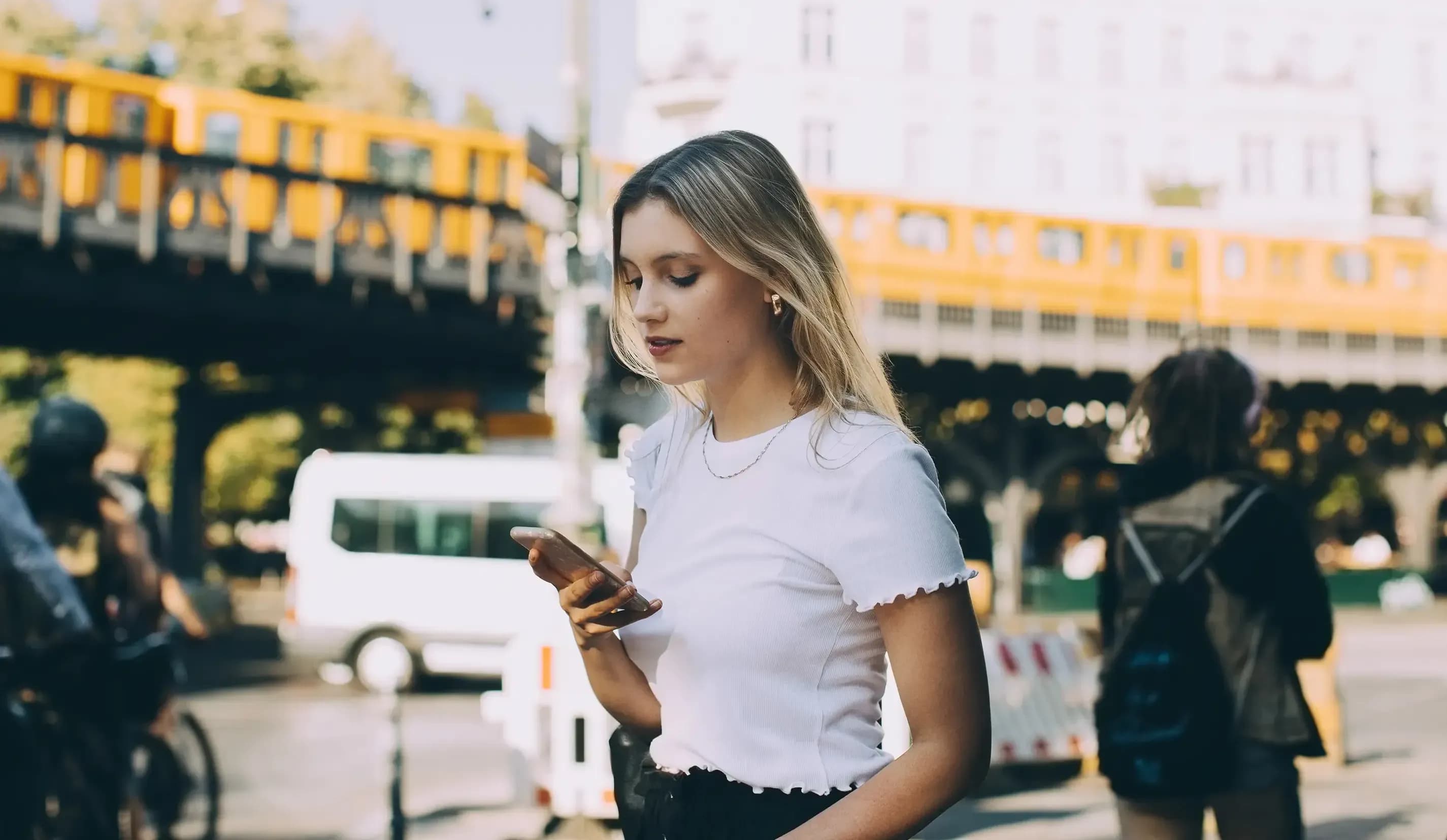 Eine Frau schaut mitten in der Stadt auf ihr Smartphone.