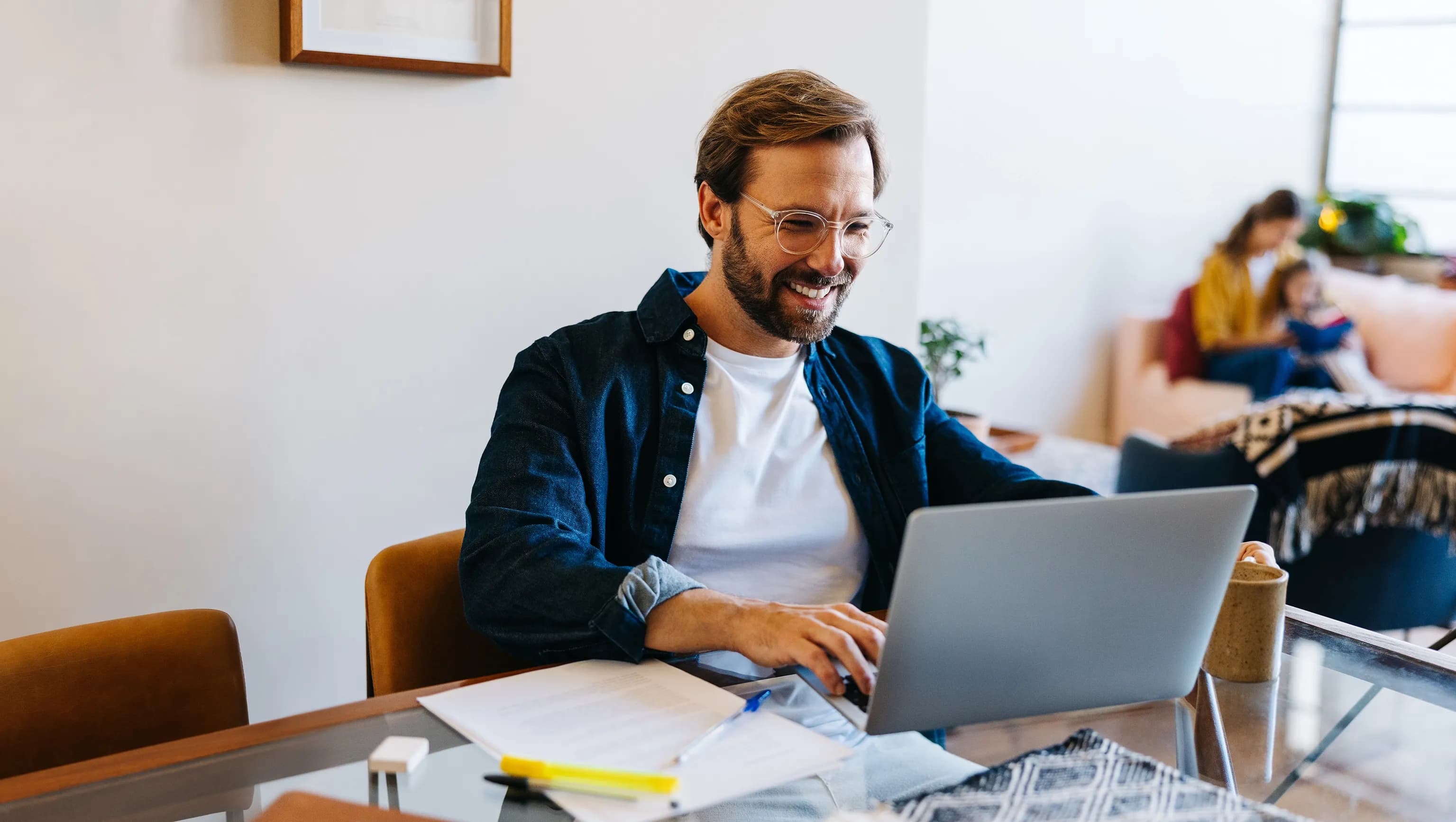 Ein Mann sitzt an einem Tisch und arbeitet an seinem Laptop.