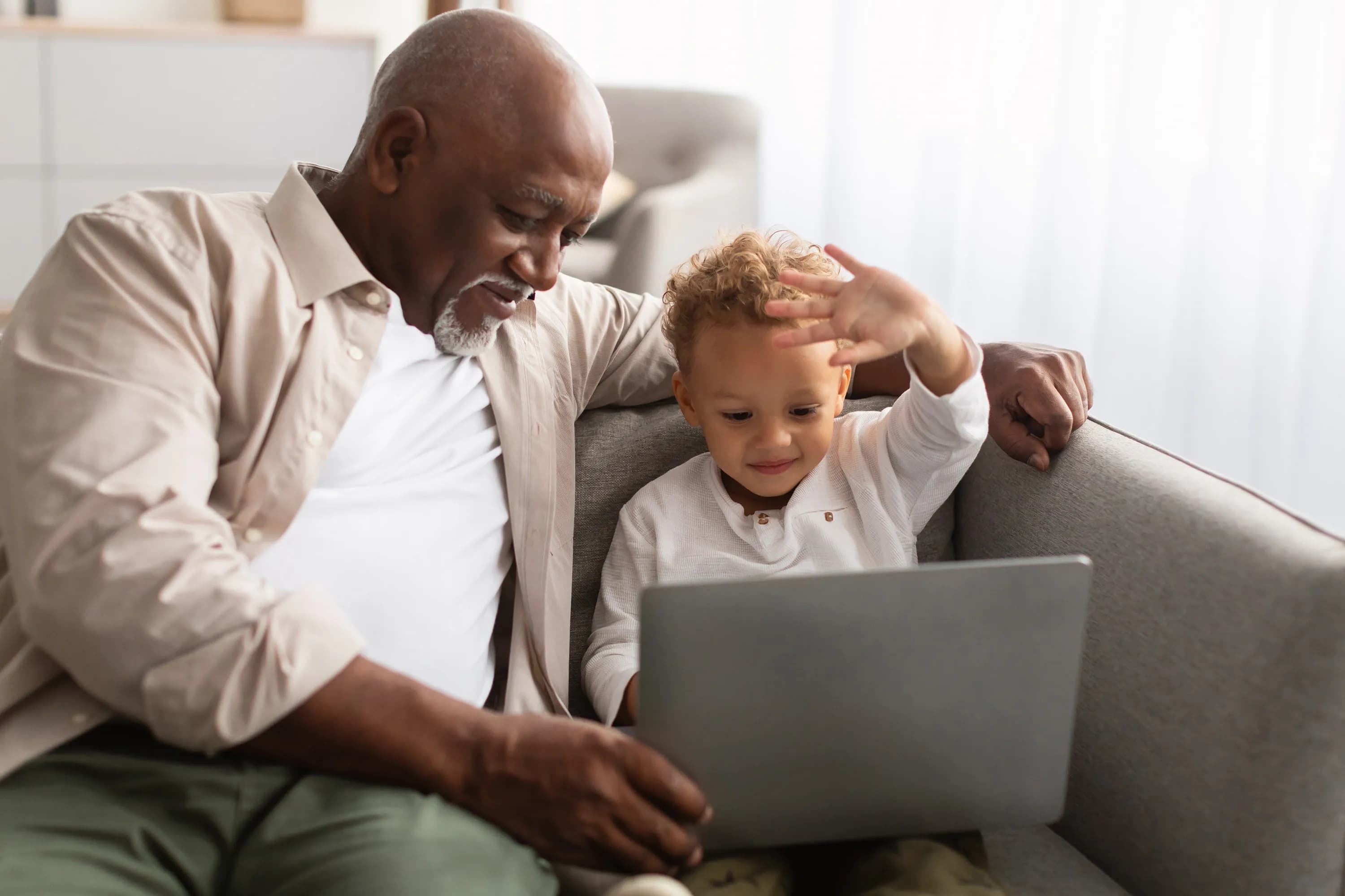 Ein Großvater und sein Enkel führen gemeinsam über einen Laptop ein Videogespräch.